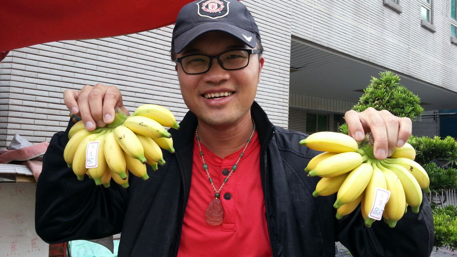 Jeff, an OWNRIDES driver, holding up two bunches of bananas while smiling