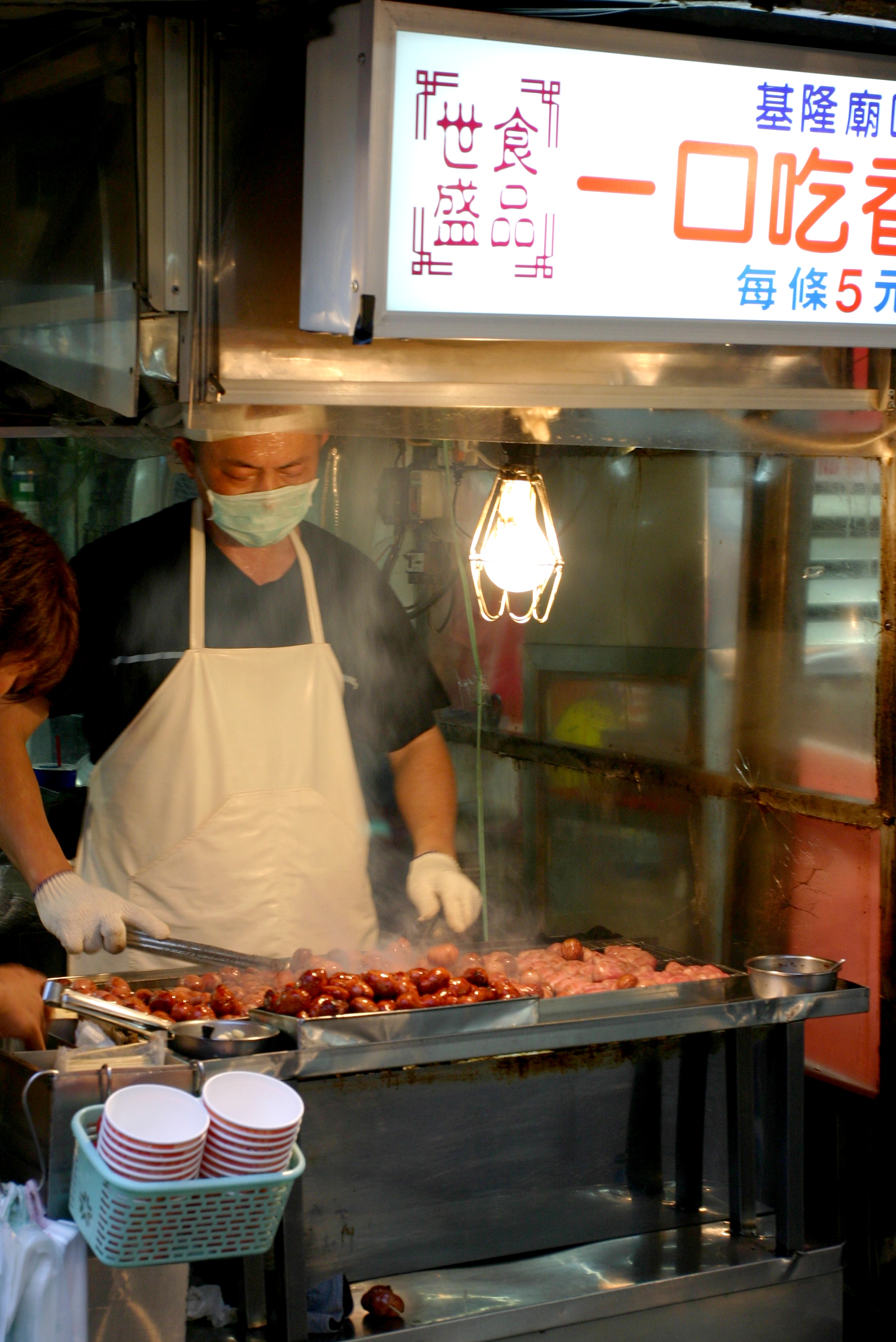 Man roasting sausages at the One-bite sausage stall in Keelung Night Market