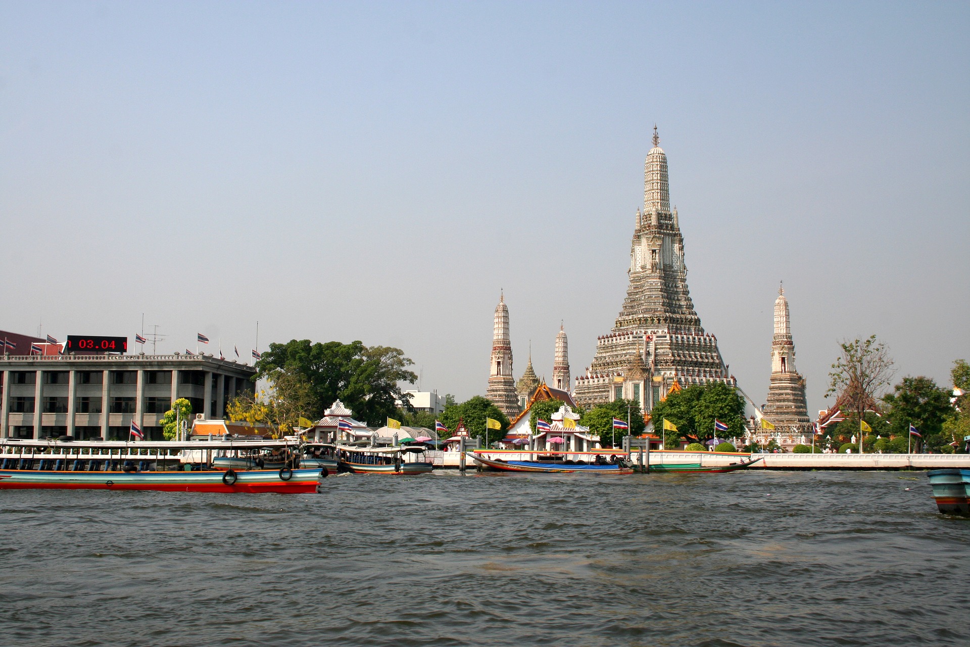 Boats cruising down the Chao Praya River, passing by the Temple of Dawn - Wat Arun 